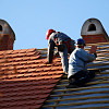 Two roofers install clay roofing tiles, a green roofing material. (Photo: majorosl/istockphoto.com)