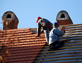 Two roofers install clay roofing tiles, a green roofing material. (Photo: majorosl/istockphoto.com)